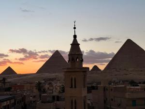 un edificio con una torre con piramidi sullo sfondo di Aida of pyramids view hotel a Il Cairo