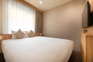 a bedroom with a large white bed with a window at Villa Fontaine Tokyo Jimbocho in Tokyo +12 photos