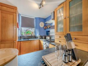eine Küche mit Holzschränken und einer Theke mit Weingläsern in der Unterkunft Slate Cottage in Windermere