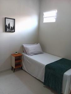 ein kleines Schlafzimmer mit einem Bett und einem Nachttisch in der Unterkunft Natal em Garanhuns, PE - Apartamento minimalista próximo ao Centro in Garanhuns