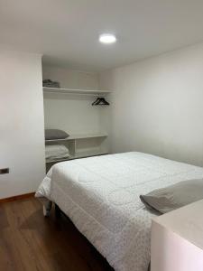 a white bedroom with a bed and shelves at Casa de Max in Valparaíso