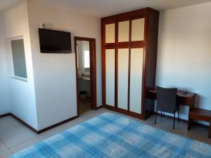a room with a bed and a desk and a television at Flat com Piscina e Academia in Uberaba