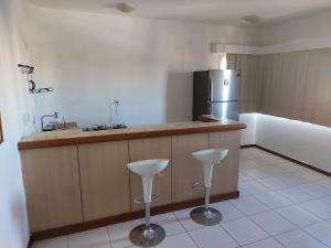a kitchen with a counter and a refrigerator and stools at Flat com Piscina e Academia in Uberaba +7 photos