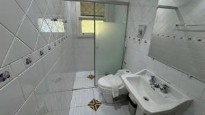 a white bathroom with a toilet and a sink at Casa Rara em Gramado, ideal para Famílias e Grandes Grupos de Viagens, com uma ampla área verde in Gramado +25 photos