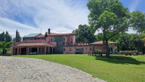 a large pink house with a tree in front of it at Casa de Campo Petit Lodge in Estancia Grande +9 photos