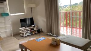 a living room with a table and a tv and a balcony at Saraswati in Nakijin