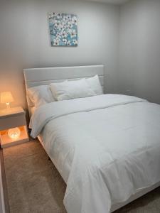 a bedroom with a white bed and a night stand at Hanan Hospitality in Toronto