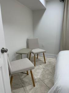 a room with two chairs and a table and a bed at Hanan Hospitality in Toronto +4 photos