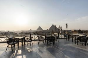 un patio con mesas y sillas con pirámides en el fondo en Pyramids Pavilion Boutique Hotel, en El Cairo