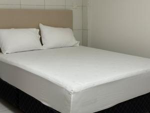 a white bed with two pillows on top of it at Alojamiento para 12 personas a pasos del Estadio Defensores del Chaco in Asuncion +14 photos