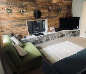 a living room with a couch and a fireplace at Nant caer Efail Cottage - Stream by the forge in Pen-y-cae +2 photos