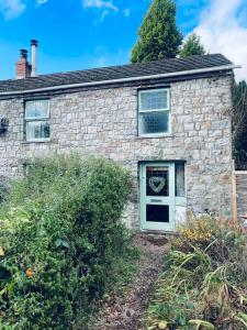a stone house with a white door and windows at Nant caer Efail Cottage - Stream by the forge in Pen-y-cae