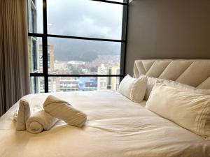 a white bed with a view of a city at Apartaestudio Centro Internacional UTEK in Bogotá
