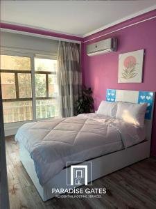 - une chambre avec un mur violet et un lit dans l'établissement Paradise Gates Madinaty, à Madinaty