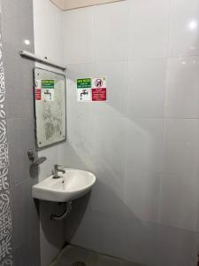 ein weißes Badezimmer mit Waschbecken und Spiegel in der Unterkunft Royal Elite Perumbakkam in Chennai