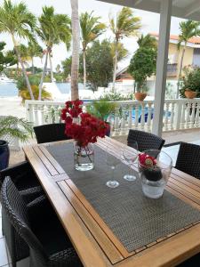 a wooden table with glasses and flowers on a table at Aqualife Best view apartment in Willemstad