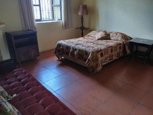 a bedroom with a bed and a couch and a window at Jardín de Los Sueños Quinta San Felipe in Antigua Guatemala +2 photos