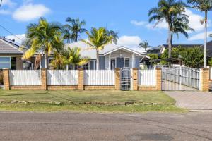 a white fence in front of a house with palm trees at Seascape Cottage - Shelly Beach in Shelly Beach +5 photos
