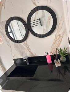 a bathroom with two mirrors and a black sink at Flat -Hidromassagem privativa e Piscina a 500 mts da praia in São Vicente