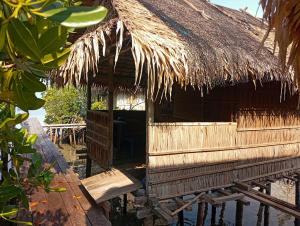 MinyaifuinにあるSeawhip Homestayの前にベンチがある茅葺き屋根の小屋