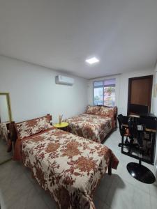 a bedroom with two beds and a desk with a computer at Apt pé na areia ao lado do Beach Park no Porto das Dunas in Aquiraz