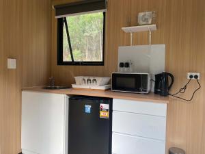 La cuisine est équipée d'un four micro-ondes et d'un réfrigérateur. dans l'établissement Wombat Hideaway by Tiny Away, à Laguna