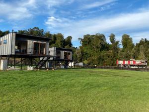 巴拉斯港Loft Río Maullín, naturaleza y descanso de la mano con la modernidad的田野旁草地上的房子