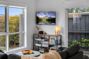 ein Wohnzimmer mit einem Sofa und zwei großen Fenstern in der Unterkunft The Bungalow in Warrnambool