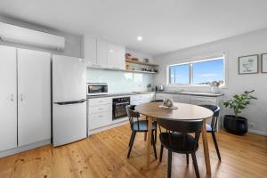 eine Küche mit weißen Schränken und einem Tisch und Stühlen in der Unterkunft The Bungalow in Warrnambool + 11 Fotos