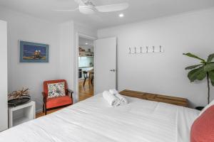 ein Schlafzimmer mit einem weißen Bett und einem Stuhl in der Unterkunft The Bungalow in Warrnambool