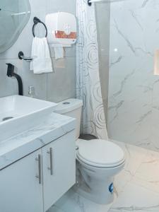 ein weißes Badezimmer mit Toilette und Waschbecken in der Unterkunft Deramai in Santo Domingo de los Colorados