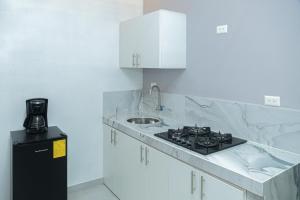 eine weiße Küche mit Spüle und Herd in der Unterkunft Deramai in Santo Domingo de los Colorados + 53 Fotos