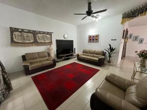 a living room with couches and a flat screen tv at Homestay Anjung Desa in Kuantan