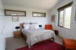 a bedroom with a bed and a red chair at Lithia Guest House - Daylesford Region in Hepburn Springs