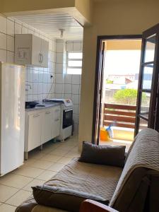 a kitchen with a couch and a refrigerator and a window at Pousada Nova in Tramandaí