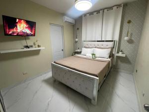 a bedroom with a bed with a tv on the wall at Apartamento cerca del aeropuerto en los frailes in Los Frailes