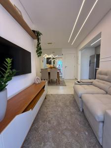 Apartamento Canto do Forte في برايا جراندي: غرفة معيشة مع أريكة وتلفزيون على الحائط
