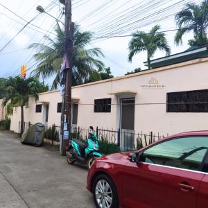 um carro vermelho estacionado em frente a um edifício com uma scooter em The Flats at 5th St em Bacolod