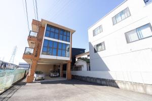 un bâtiment blanc avec une voiture garée à côté dans l'établissement Miraie Katano Stay, à Kisabe