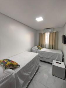 a room with two beds and a television in it at Hotel Pousada Velas ao Mar in Maceió