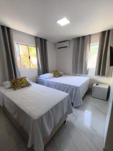 two beds in a room with two windows at Hotel Pousada Velas ao Mar in Maceió +6 photos