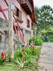 a pink house with flowers in front of it at Chalés Duquesa do Vale in Campos do Jordão