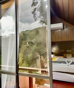 a room with a view of a mountain through a window at Chalés Duquesa do Vale in Campos do Jordão