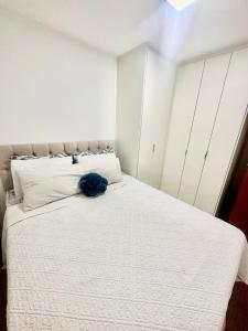 a bedroom with a white bed with a blue pillow on it at 1706 -Lindo apartamento próximo Tietê e Anhembi in São Paulo