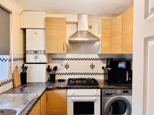 een keuken met een fornuis, een wasmachine en een droger bij Cozy Nest in Grays Thurrock