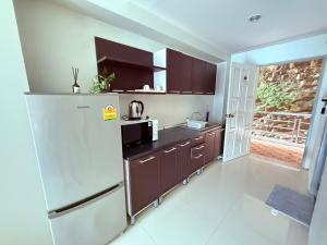 a kitchen with a white refrigerator and brown cabinets at Aonang Mountain View A5 in Ao Nang Beach