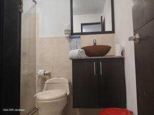 une salle de bain avec un lavabo, des toilettes et un miroir dans l'établissement Gran Hotel Coral, à Popayan 25 autres photos