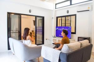 two people sitting in a living room watching a tv at Lamoon Village Khaoyai บ้านละมุน เขาใหญ่ in Pak Chong