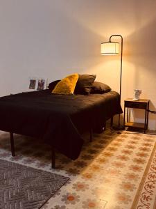 Una cama con una manta negra y una lámpara en una habitación. en Lartbook, en Monterrey