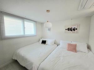 ein weißes Schlafzimmer mit zwei Betten und einem Fenster in der Unterkunft 2 Bathrooms & 3 Rooms, New Elevator in Seoul